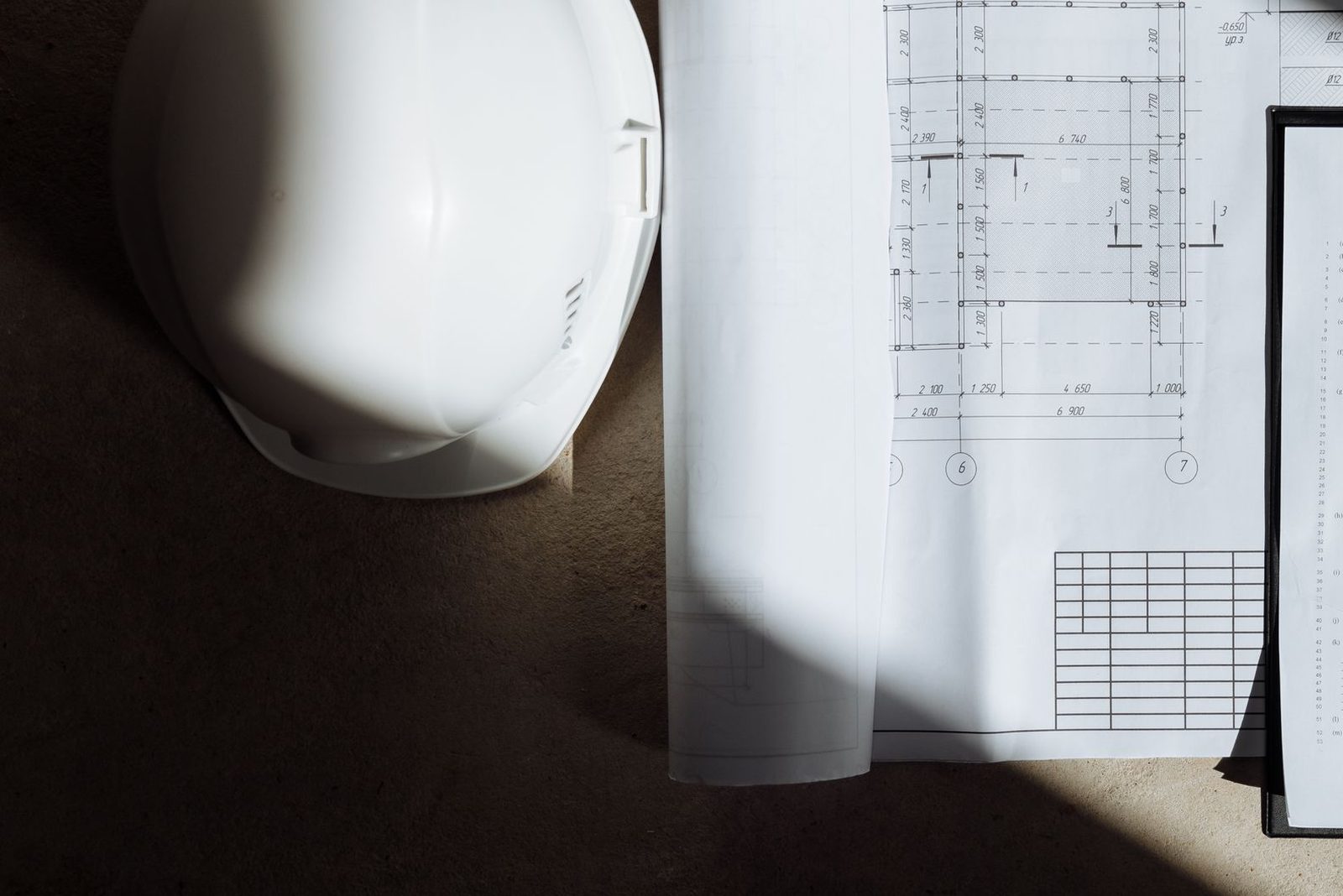 Floor plans, keys, and a hard hat on a job-site floor